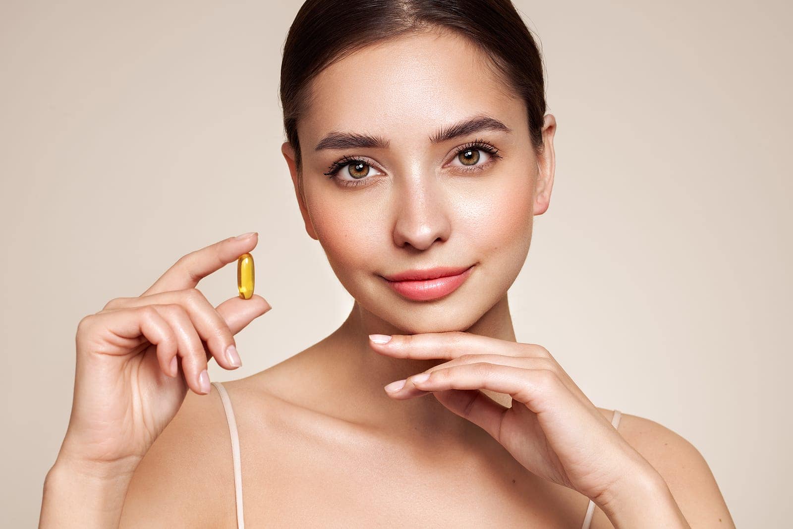 Close up of happy beautiful woman with fish oil pill