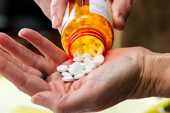 Prescription opioid tablets spilling from a bottle, illustrating drug-free alternatives for spine pain
