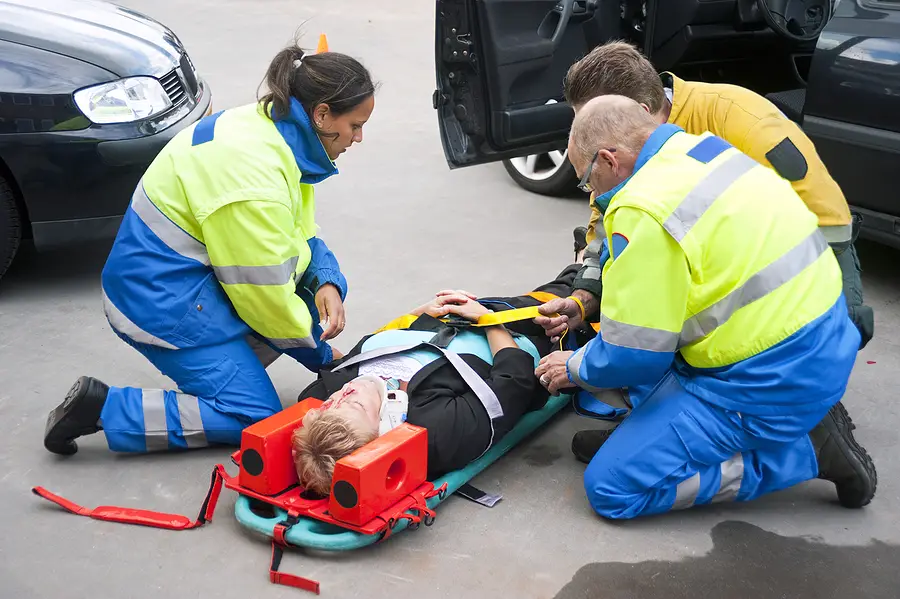 woman lying on a stretcher with neck immobilised and 3 paramedics attending to her