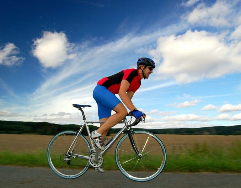 a cyclist riding a bicycle up off his seat with a countyside background